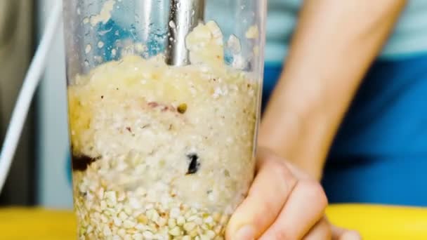 Mujer mezcla una papilla licuadora con frutas secas, un estilo de vida saludable. Chica prepara un batido para el desayuno, una dieta saludable primer plano — Vídeos de Stock