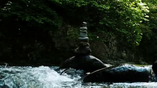 Tower or cairn stands on a cobblestone in a mountain river, slow motion — Stock Video