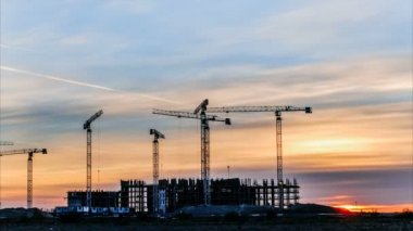 İnşaat vinçleri, günbatımında çalışan işçilerin inşaat, zaman atlamalı nişanlı.