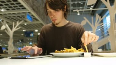 Beyaz adam hızlı yemek yeme ve tablet café'de kullanma