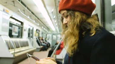 Kadın metroda bir smartphone kullanarak kulaklık ile