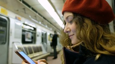Güzel genç kadın bir smartphone metro yakın çekim kullanır, bir kız telefonda bir ileti yazdırır