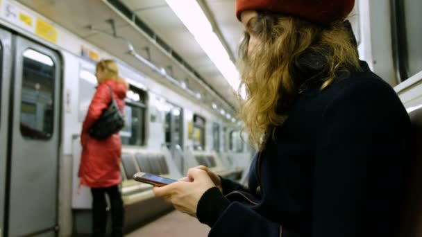 ผู้หญิงใช้สมาร์ทโฟนในรถไฟใต้ดิน ผู้หญิงใช้โทรศัพท์ในรถ — วีดีโอสต็อก