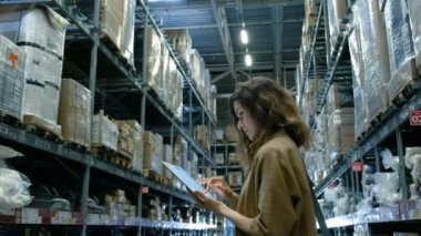 Güzel kadın bir tablet bilgisayar pc depoda seyir kullanır