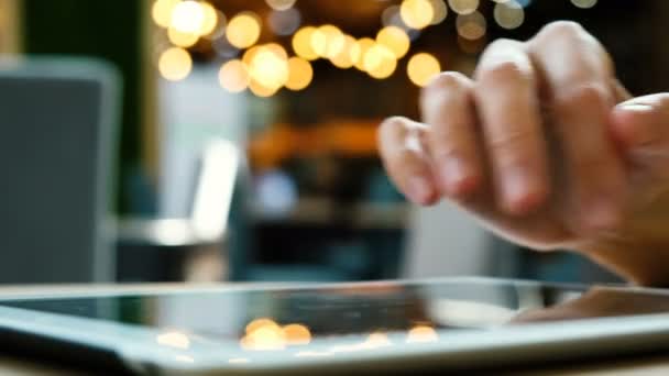 Mujer mano utiliza una PC tableta en un café sobre un fondo borroso primer plano — Vídeos de Stock