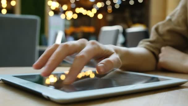 Mulher mão usa um computador tablet pc em um fundo embaçado close-up — Vídeo de Stock