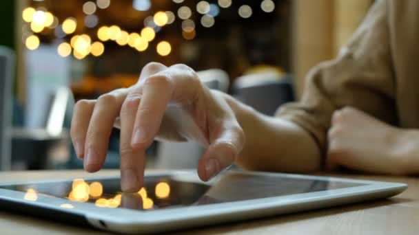 Mujer utiliza una PC tableta en un fondo borroso en la cafetería, primer plano — Vídeo de stock