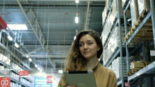 Mooie vrouw met een tablet-pc computer op zoek naar een product op voorraad — Stockvideo