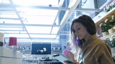 Güzel kadın bir mum bir raf mağaza bir tablet pc ile alır