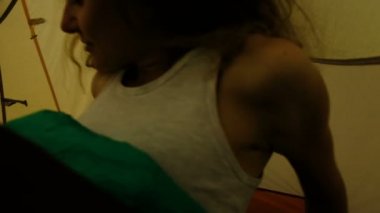 Mutlu turist kız uyku tulumu içinde uyanır, bir çadır açılır ve bir kamp içinde yüksek bir dağın arka plan üzerinde bakıyor