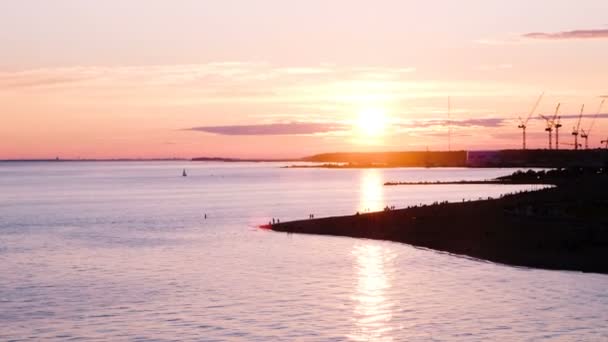 Incredibile tramonto sulla spiaggia della città sulle rive della baia, vela e persone si rilassano — Video Stock