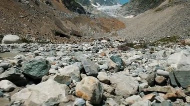 Buzul, ağır çekim arka plan üzerinde dağlarda taşlı söylüyor. Dağ dere ve kır çiçekleri, kamera hareketi