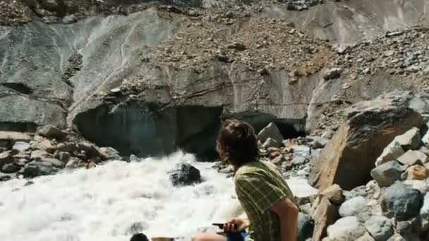 O homem olha para as pedras a cair do glaciar. Rockfall em um ponto turístico — Vídeo de Stock
