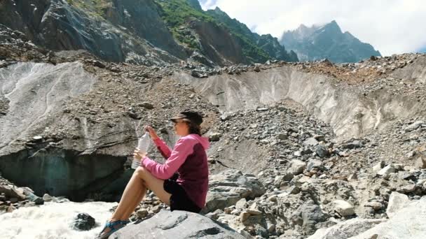 Дівчина-турист п'є воду з пляшки в горах, повільний рух — стокове відео