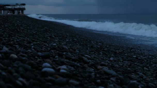 Волны бьются на гальке в шторм на море на фоне дождевых облаков — стоковое видео