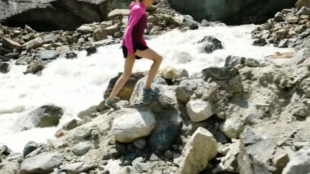 Flicka turist klättrar upp stenar i bergen — Stockvideo