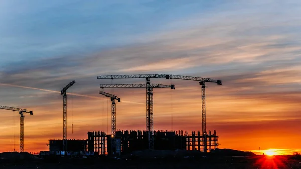 Żurawie budowlane pracę o zachodzie słońca, pracownicy zaangażowani w budowę, upływ czasu — Zdjęcie stockowe