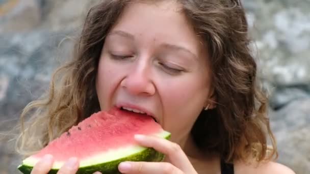 Gros plan portrait d'une belle femme bouclée mordant une pastèque — Video