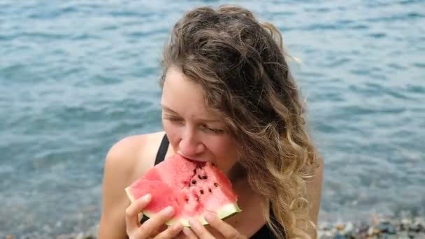 Porträt einer schönen lockigen Frau, beißt eine Wassermelone in Zeitlupe ab — Stockvideo