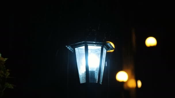 Rain drops hit the street lamp, the light illuminates the spray — Stock Video