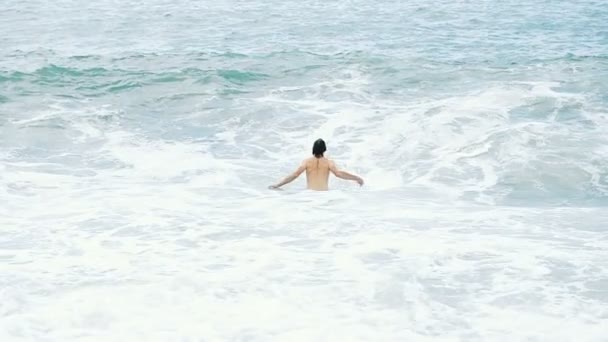 Man turist dyker ner en stor sea wave täcker huvudstupa, Slowmotion — Stockvideo