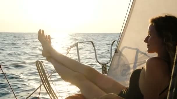 Donna in costume da bagno prende il sole su uno yacht a vela al tramonto in mare — Video Stock