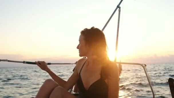 Felice donna sorridente in costume da bagno si siede su uno yacht e gode di una vista al tramonto — Video Stock