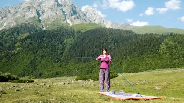 Traveler samlar tält på bakgrund av höga berg — Stockvideo