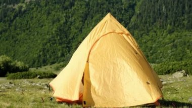 Uykulu turist kadın çadır açılır ve arka plan kamp alanında yüksek bir dağın üzerinde sabah bakıyor.
