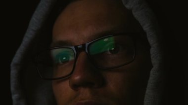 Karanlıkta, gözlük yakın çekim, 4 k bir yansıması bir bilgisayar programcısı gözlük ve bir başlık ile çalışıyor