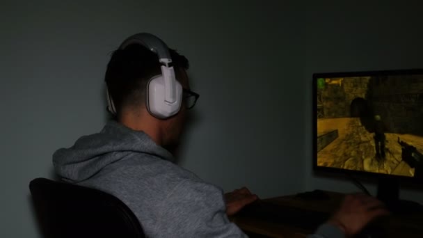 El hombre de los auriculares juega en los juegos de ordenador en la oscuridad, 4k — Vídeo de stock