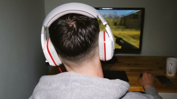 El hombre de los auriculares juega en los juegos de ordenador en la oscuridad, la vista trasera, 4k — Vídeo de stock