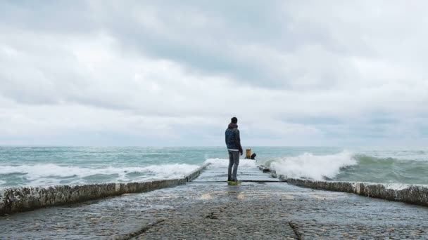 Vrolijke man loopt weg van de grote golven op het dok, langzame motie — Stockvideo