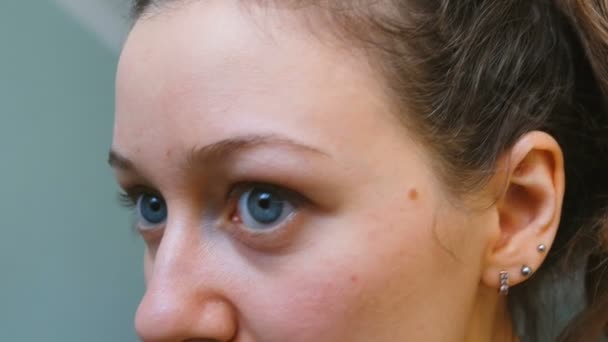 Hermosa chica con ojos azules tira de las cejas de cerca, 4k — Vídeo de stock