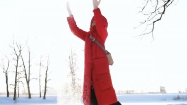 Bir kırmızı ceket aşağı kız mutlu gün batımı, ağır çekim, kışın kar atıyor