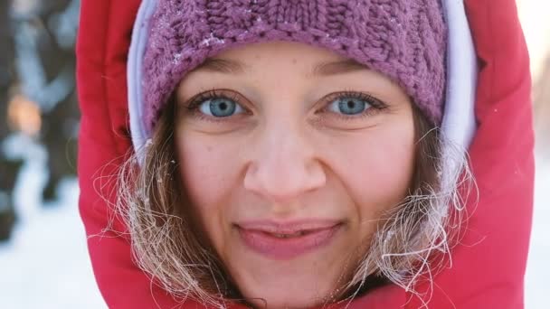 Retrato de uma linda menina caucasiana com olhos azuis inverno frio em um parque de close-up, câmera lenta — Vídeo de Stock