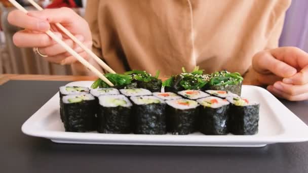 Девушка ест морские водоросли палочками в японском ресторане — стоковое видео