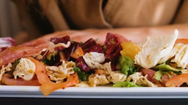 Chica comiendo una ensalada con palitos de pescado crudo en un primer plano restaurante — Vídeos de Stock