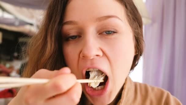 Mooi meisje met blauwe ogen salade stokken eten in een café-restaurant — Stockvideo