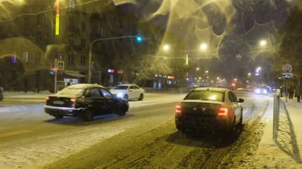 Verschneiter Abend in der Stadt, Autos fahren auf verschneiter Straße — Stockvideo