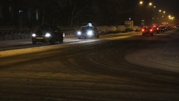 Los coches van lentamente a la nieve en un camino nevado tarde en la noche, cámara lenta — Vídeos de Stock