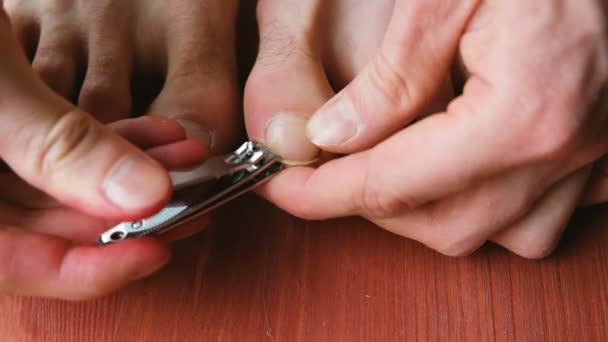 L'homme se coupe soigneusement les ongles des orteils en gros plan. Un homme se fait une pédicure à la maison sur le sol — Video