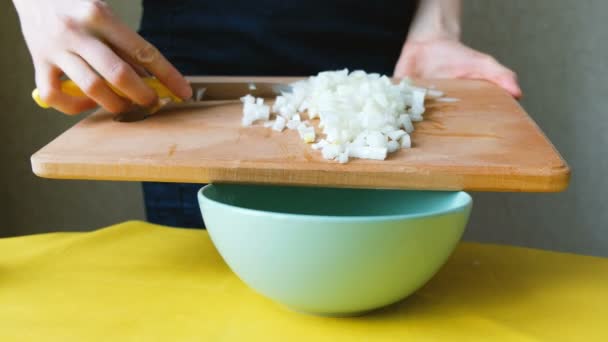 Vrouw chef-kok vegen de gesneden ui uit een snijplank in een plaat — Stockvideo