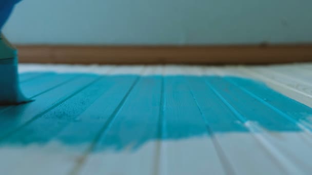 Schilder stations borstel langs een schone houten plank met turquoise verf in slow motion — Stockvideo