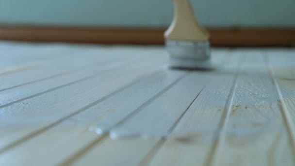 Girl paints a wooden floor with white paint in slow motion, close-up — Stock Video