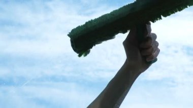 Adam lathers, kirli cam balkon bir bez ile yakın çekim endüstriyel bir tırmanıcı camdan dışarı yıkar.