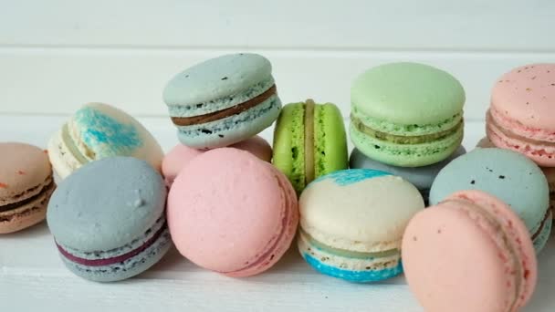Multicolored macaroons or macarons lie on a white wooden background, a row of almond cookies. Video in slow motion — Stock Video