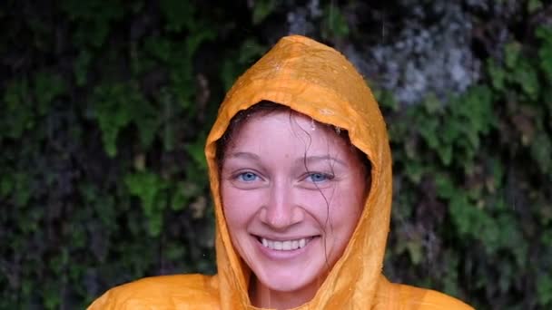 Närbild porträtt av en kvinna i en gul regnjacka ser ut och ler, Slowmotion — Stockvideo