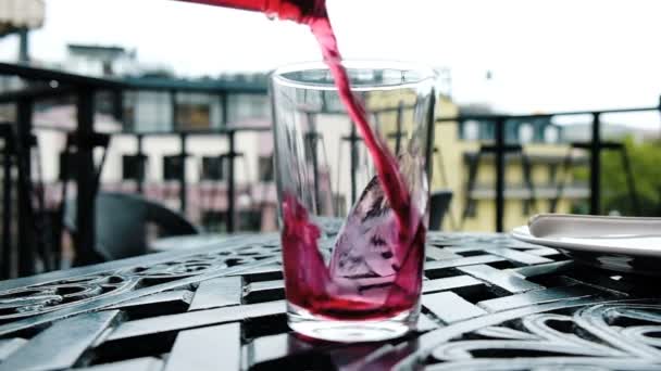 Cherry koolzuurhoudende drank wordt gegoten in een glazen uit een fles, slow-motion — Stockvideo
