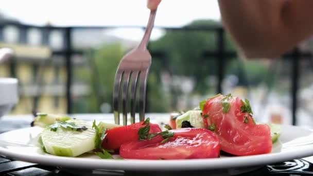 Mujer en un restaurante come ensalada de pepinos y tomates con un tenedor de cerca — Vídeo de stock